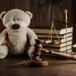 Teddy bear on desk with gavel and scale
